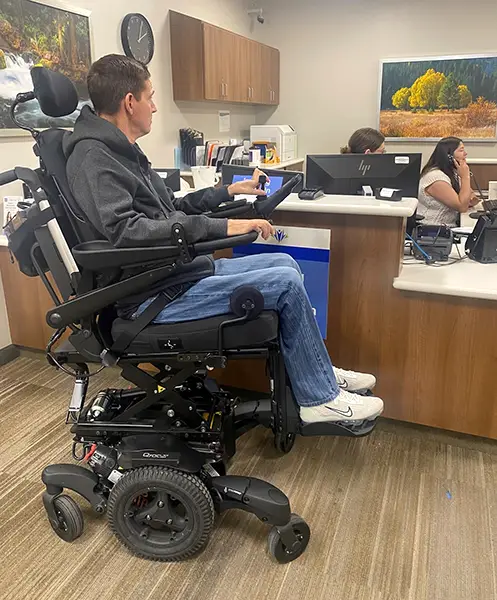 Lonnie interacting over a high counter with his seat elevated