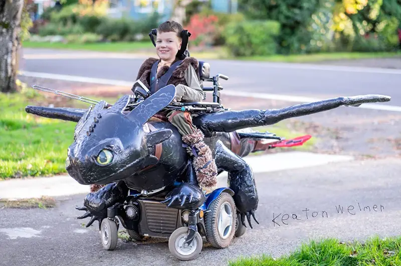 A young boy in his dragon-themed wheelchair costume