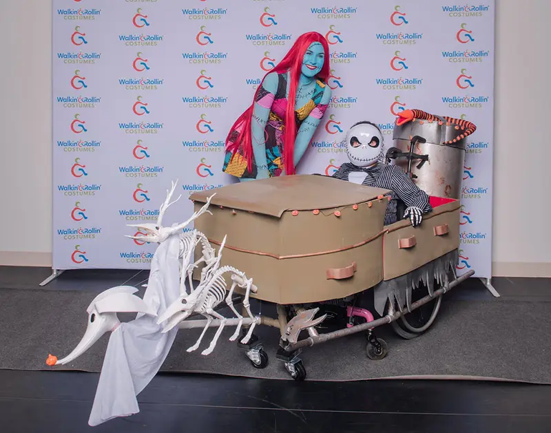 A young boy in his wheelchair costume with another costumed woman