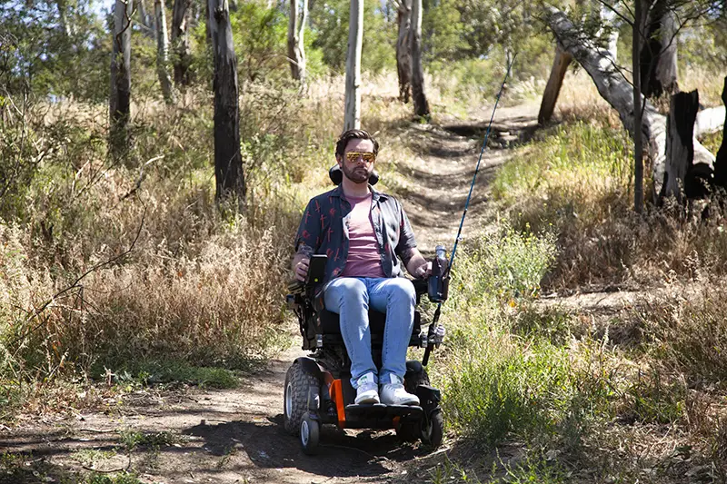 A man using a power wheelchair to navigate an off-road trail