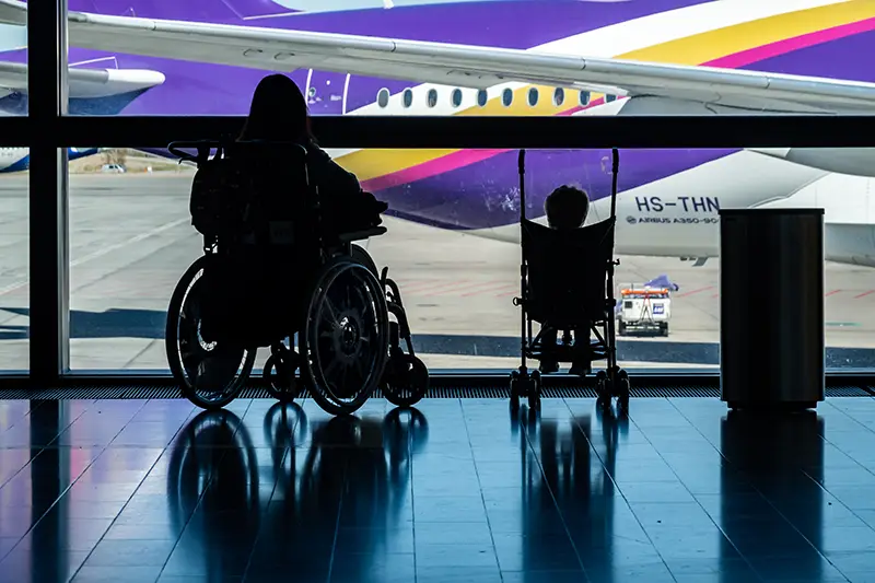 A woman using a wheelchair and a young child in a stroller at an airport