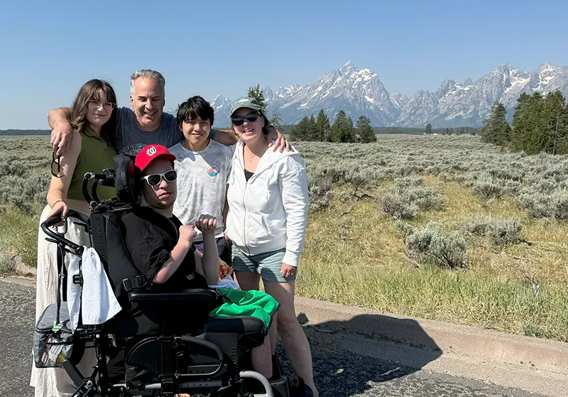 Rachel and her family taking a photo in front of a mountain range